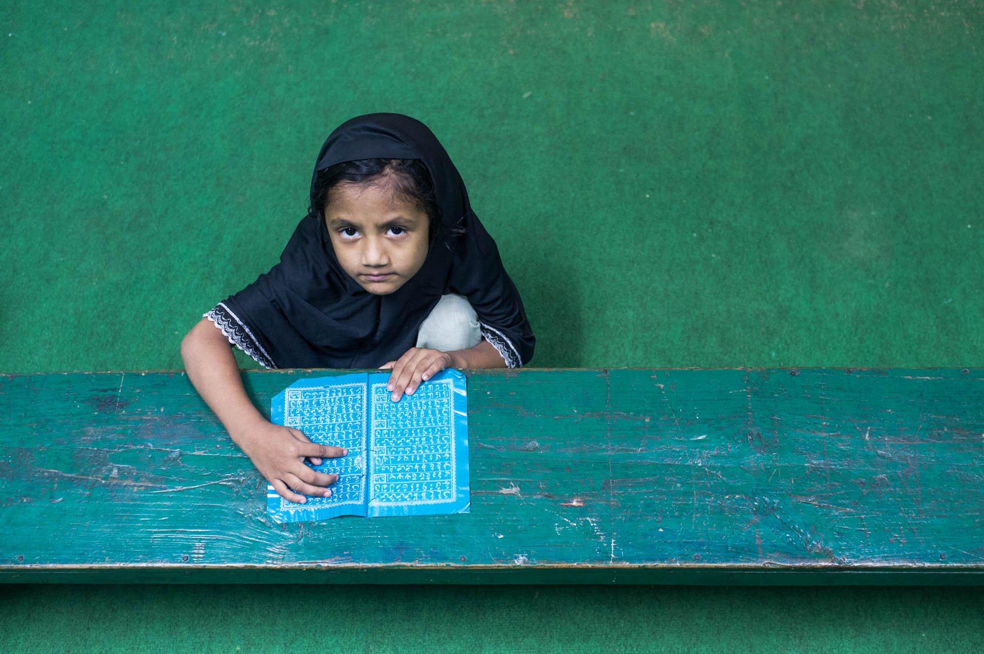 Girl reading at a madrasa bench